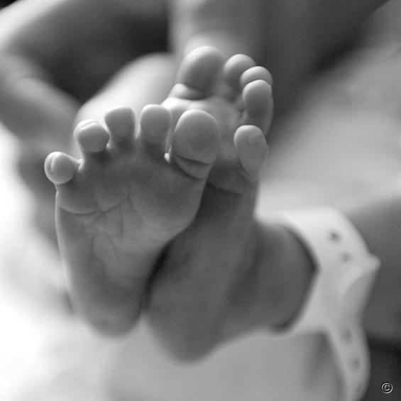 Twee babyvoetjes in de lucht met aan het enkeltje het ziekenhuis kaartje.